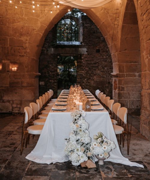 Ein langer Tisch in einem alten Steinhaus, elegant dekoriert.